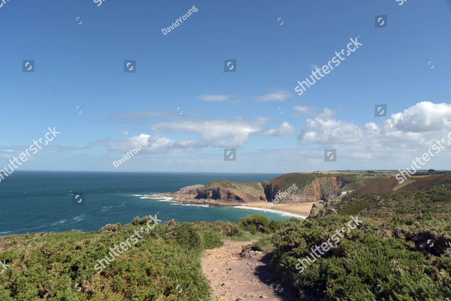 A coastal footpath leading down to a sunny bay